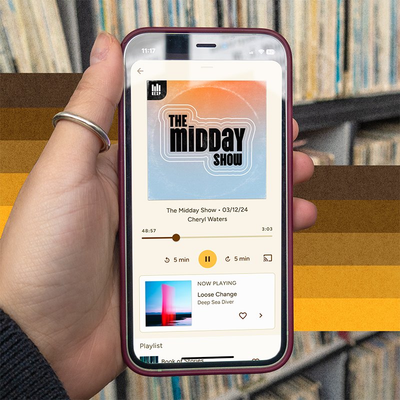 iPhone 12 mini displaying the mobile app with the Midday Show playing